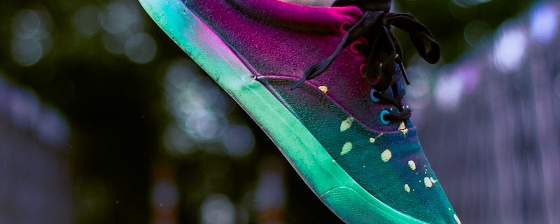 selective focus photography of person wearing multicolored sneakers while jumping