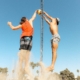 man in orange t-shirt and blue denim shorts holding silver pole during daytime