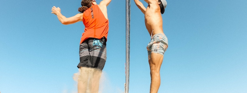 man in orange t-shirt and blue denim shorts holding silver pole during daytime