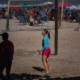 woman in blue tank top and black pants standing on beach during daytime