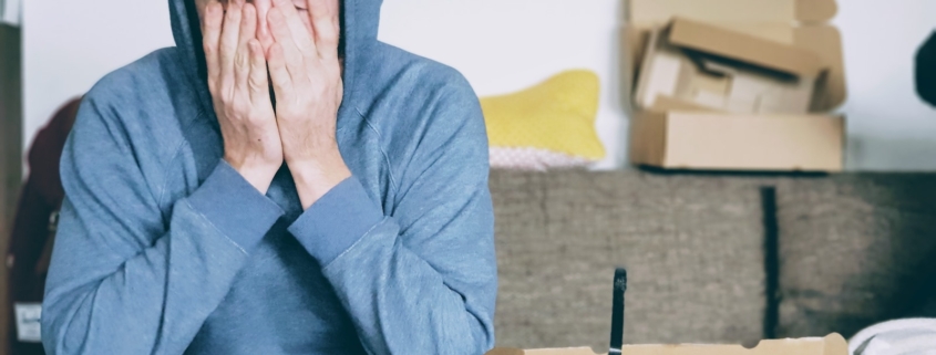 man covering face with both hands while sitting on bench